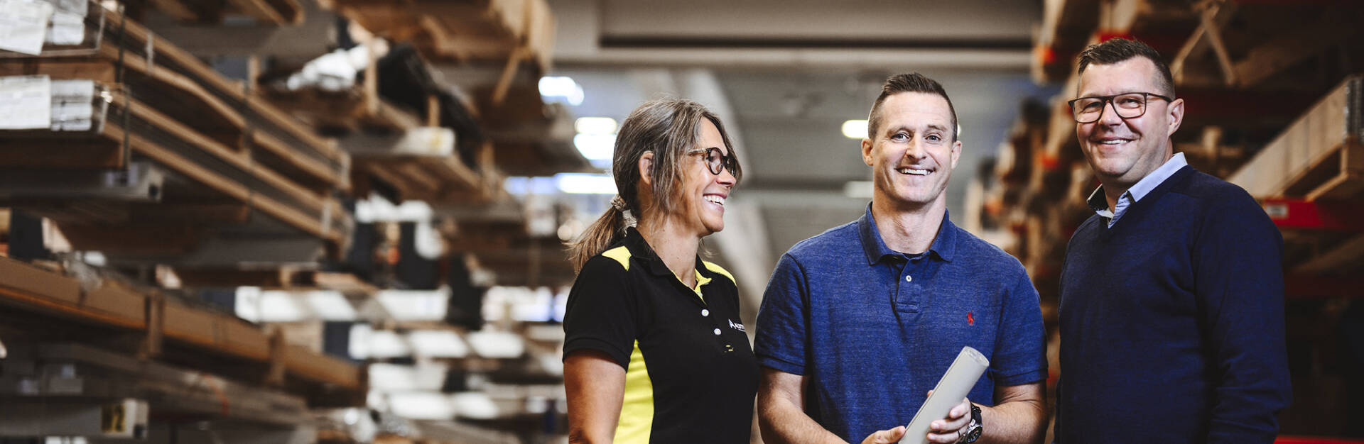 Tre leende personer ur Alutrades personal i lagerlokalen.&nbsp;